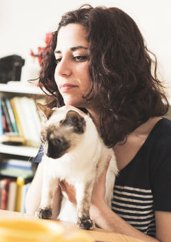 Jeune étudiante avec son chat devant son ordinateur