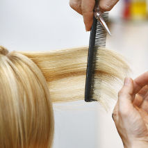 Coiffeur qui peigne les cheveux d'une cliente