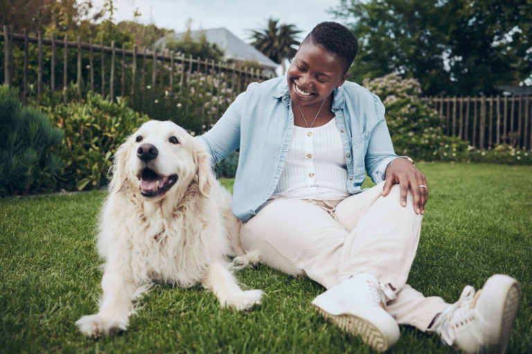personne assise avec un chien dans l'herbe
