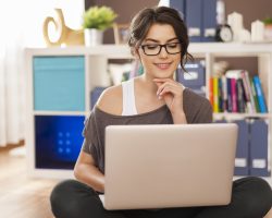 Smiling woman using laptop on floor at home e learning